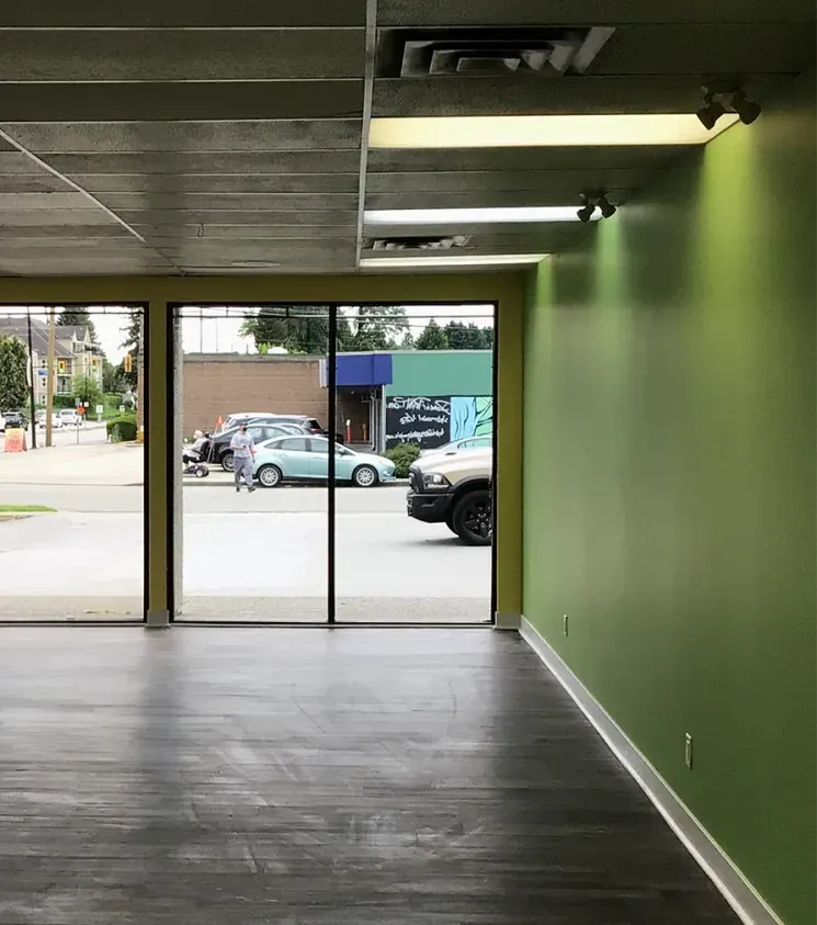 Vacant commercial unit with a freshly painted green wall, new flooring and storefront windows