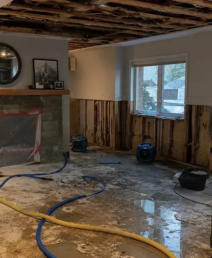 Water-damaged living room with the wet drywall cut away and drying fans running