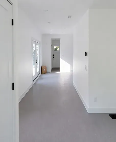 Freshly painted white hallway with new baseboards and grey flooring