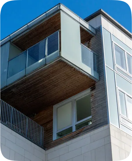Modern multi-storey building with wood and panel cladding, glass balconies and a stone base