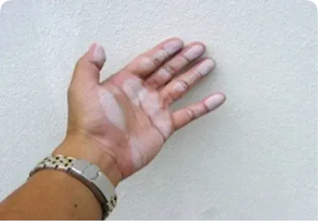 Close-up of a hand touching a wall with chalky, worn paint residue